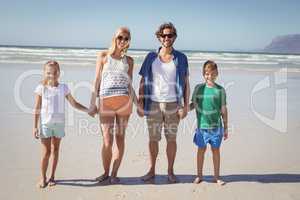 Portrait of family holding hands while standing together at beach