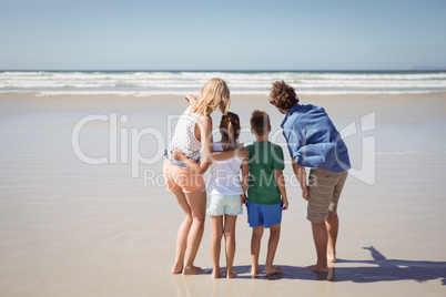 Rear view of family standing together at beach