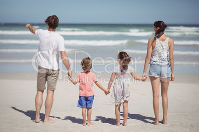 Man pointing away while standing with family at beach