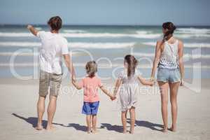 Man pointing away while standing with family at beach