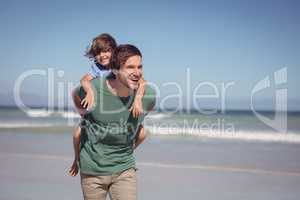 Happy young father piggybacking his son at beach