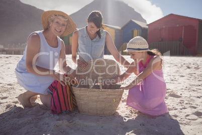Multi-generation family by picnic basket on sand at beach