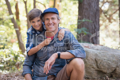 Smiling father and son hiking in forest