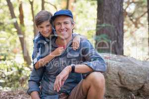Smiling father and son hiking in forest