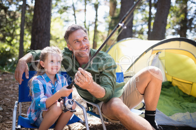 Father and daughter fishing at campsite in forest