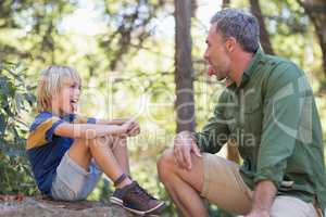 Father and son sticking out tongue while sitting in forest