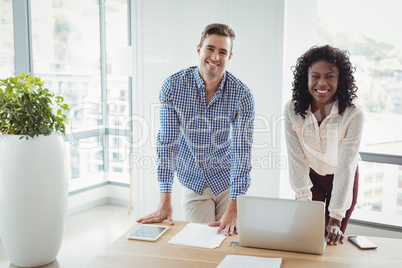 Portrait of smiling executives standing at desk