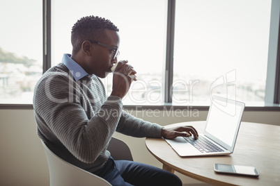 Attentive executive drinking coffee while using laptop