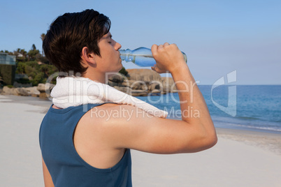 Man drinking water from bottle on beach