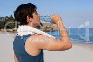 Man drinking water from bottle on beach