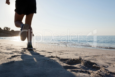 Man jogging on beach against blue sky