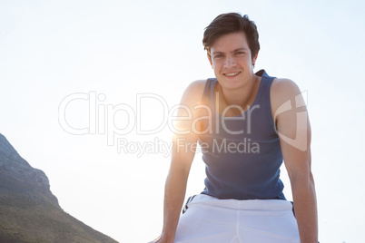 Smiling man taking break after jogging on beach