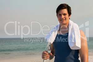 Smiling man holding water bottle on beach