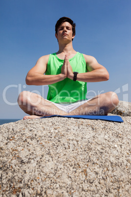 Man performing yoga on rock