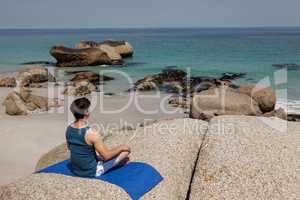 Man performing yoga on rock