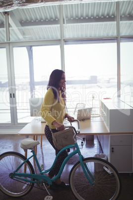 Young businesswoman with bicycle in creative office