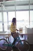 Young businesswoman with bicycle in creative office