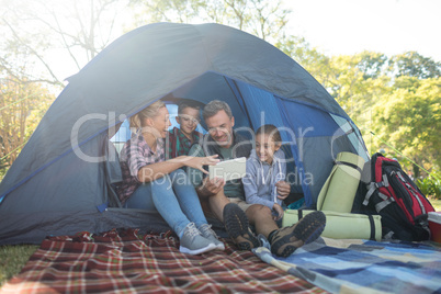 Family looking at the digital tablet in the tent