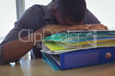 Businessman sleeping on files in office