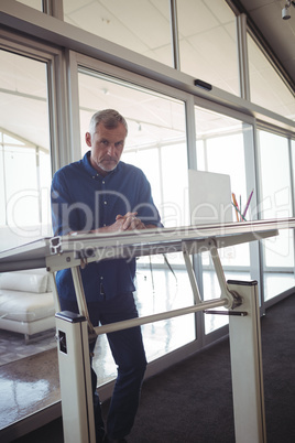 Mature businessman standing by workbench in office