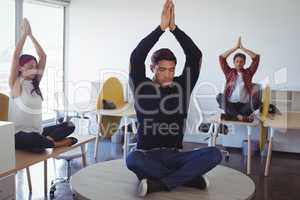 Business colleagues doing yoga at office