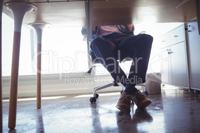 Low section of businessman sitting at desk in office