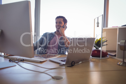 Young businessman talking on mobile phone while working at office
