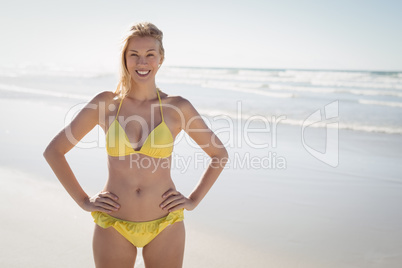 Portrait of smiling young woman in yellow bikini standing at beach