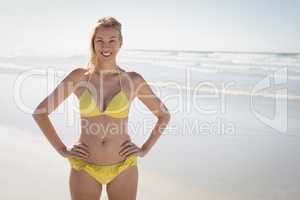 Portrait of smiling young woman in yellow bikini standing at beach