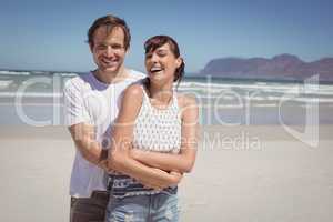 Portrait of cheerful couple embracing at beach