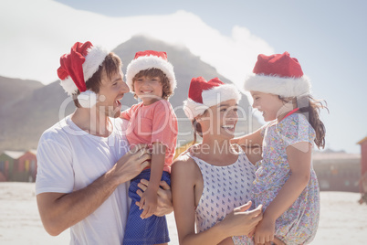 Happy children with parents wearing Santa hat at beach