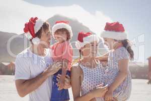 Happy children with parents wearing Santa hat at beach