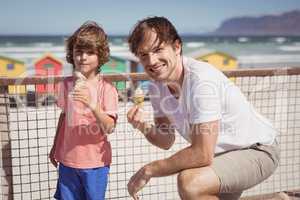 Portrait of father with son eating ice cream by railing