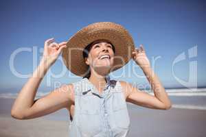 Happy woman wearing sun hat at beach