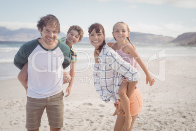 Portrait of young parents piggybacking their children