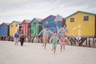Happy multi-generation family running by beach huts at beach