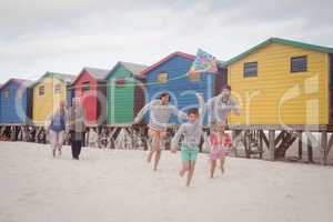 Happy multi-generation family running by beach huts at beach