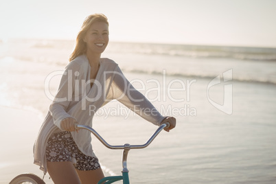 Portrait of smiling woman riding bicycle at beach