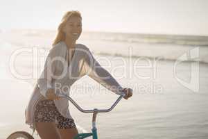 Portrait of smiling woman riding bicycle at beach