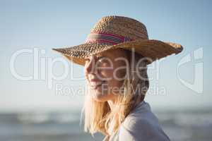 Happy woman looking away while wearing sun hat at beach