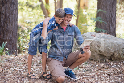 Father and son reading map while hiking in forest