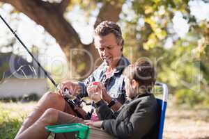 Father and son holding fishing equipment on sunny day