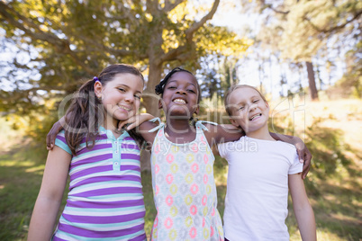 Smiling girls standing in forest on sunny day