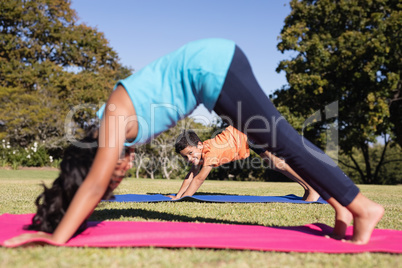 Boy looking through girl practicing yoga on mat