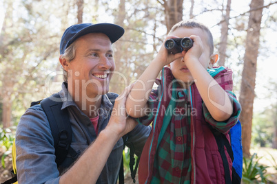 Happy man watching son looking through binoculars