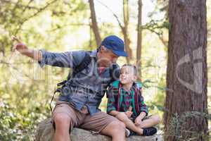 Father and son sitting on rock while pointing away