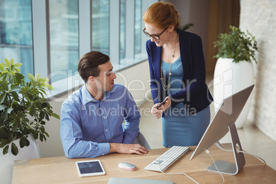 Executives discussing over mobile phone at desk