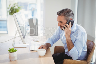 Executive talking on mobile phone at desk