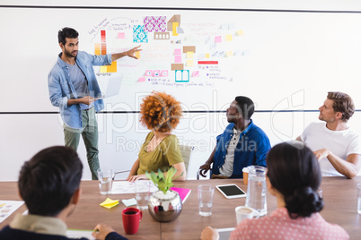 Colleagues looking at businessman during meeting in office