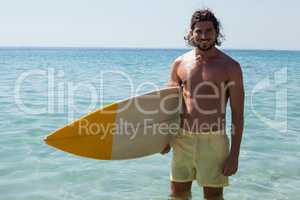 Smiling surfer with surfboard standing at beach coast